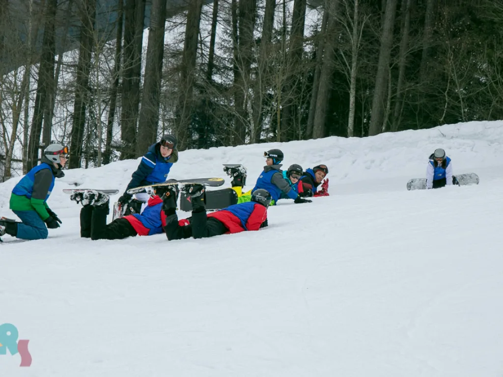 Snowboardgruppe macht am Pistenrand Pause.